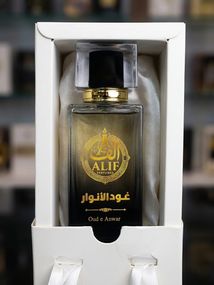 A bottle of ALIF Perfumes Oud e Anwar fragrance presented inside a white gift box with satin lining, set against a blurred background.