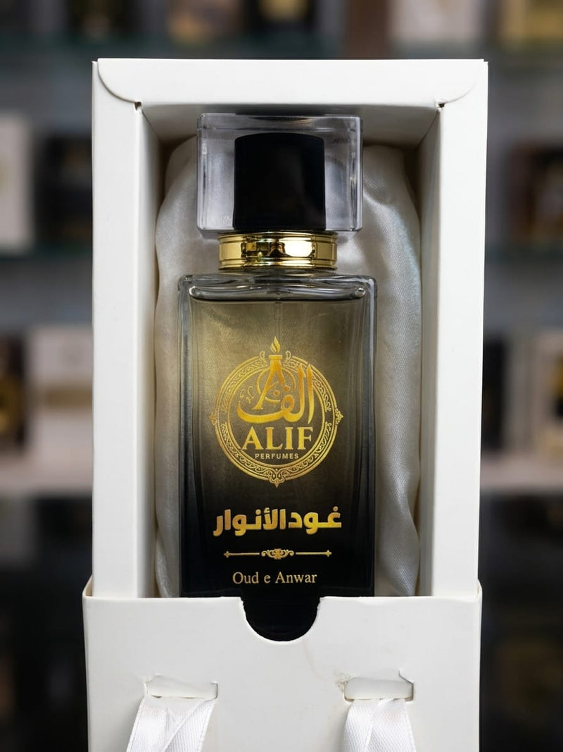 A bottle of ALIF Perfumes Oud e Anwar fragrance presented inside a white gift box with satin lining, set against a blurred background.